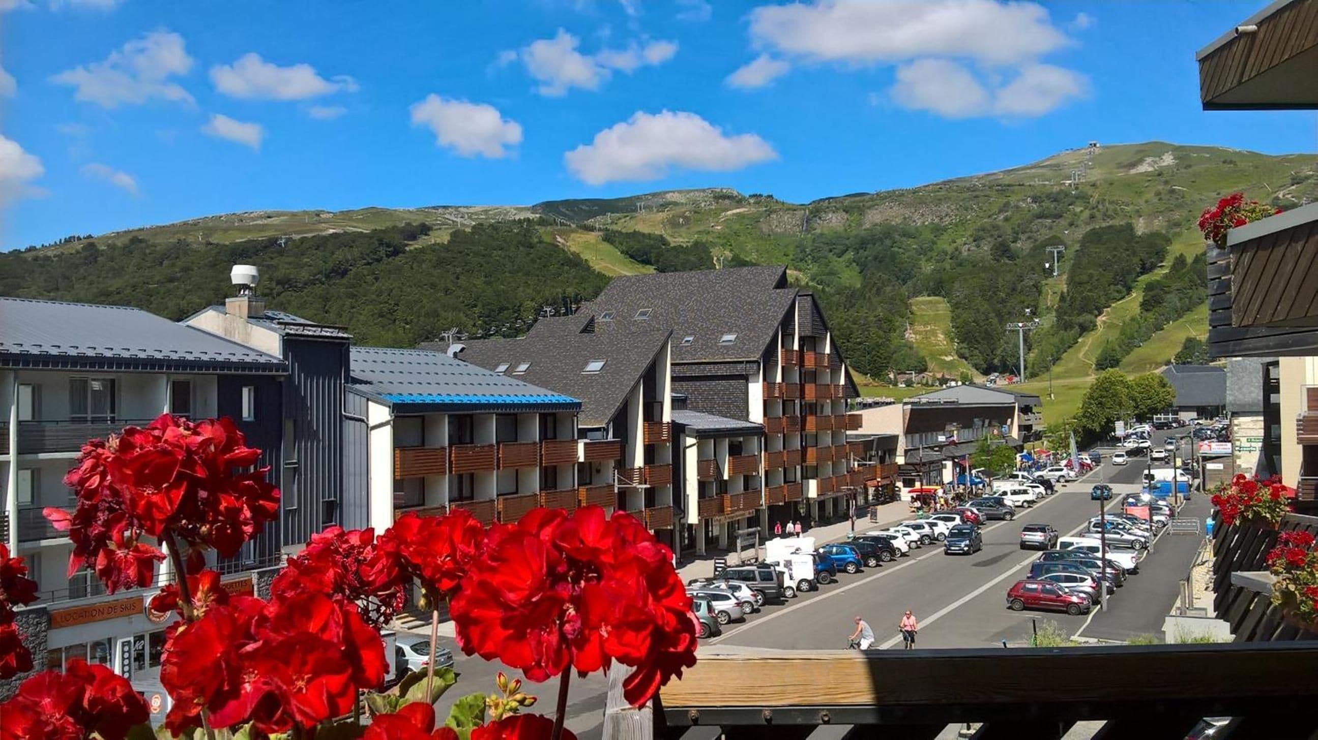 A street view with buildings, cars, and a mountainous backdrop.