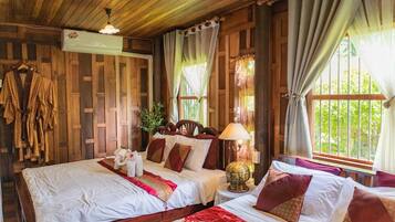 A room with two beds, wooden walls, a hanging towel rack, a globe lamp, and a window with curtains.