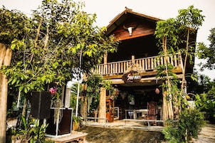 A rustic building with a wooden balcony, surrounded by lush greenery and a sign that reads "Land Safari."