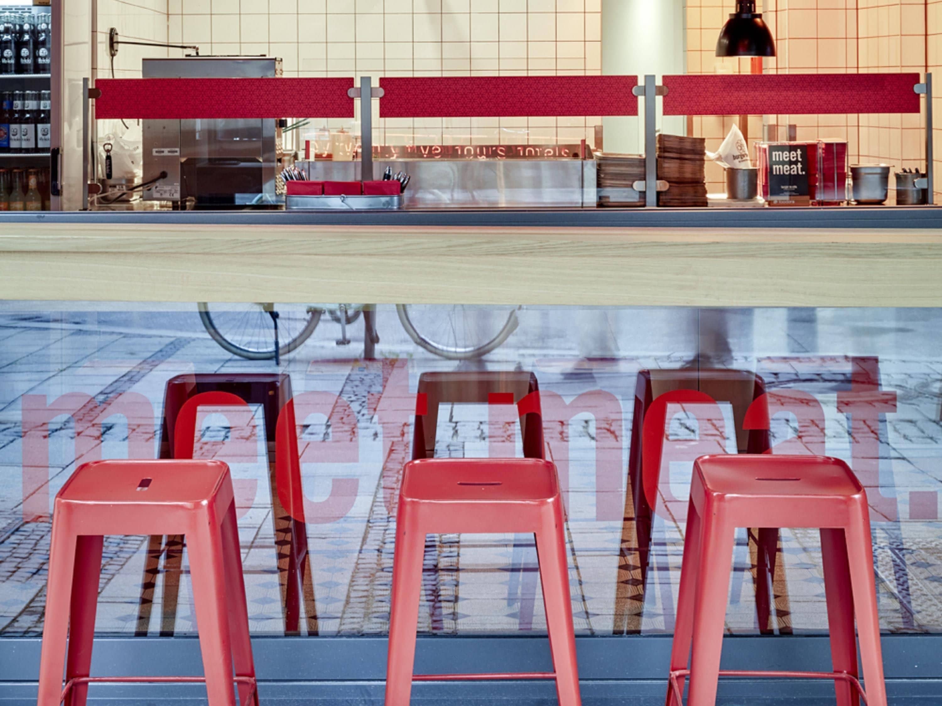 Mostrador con tablero de menú, taburetes rojos y una bicicleta al fondo.