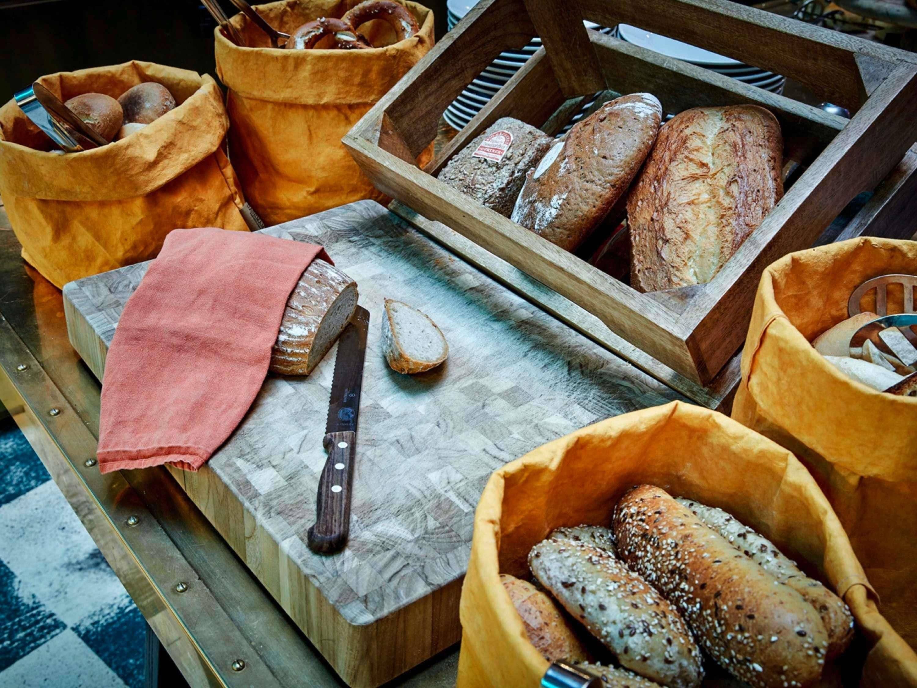 Verschiedene Brotsorten und ein Messer auf einer Holztischplatte.