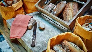 A variety of breads and a knife on a wooden surface.