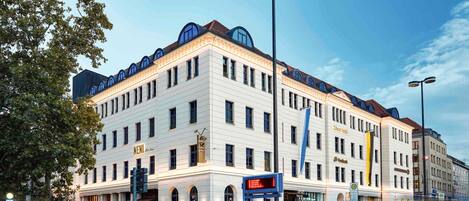 A multi-story hotel with a classic architectural design, featuring a prominent entrance and a large sign.