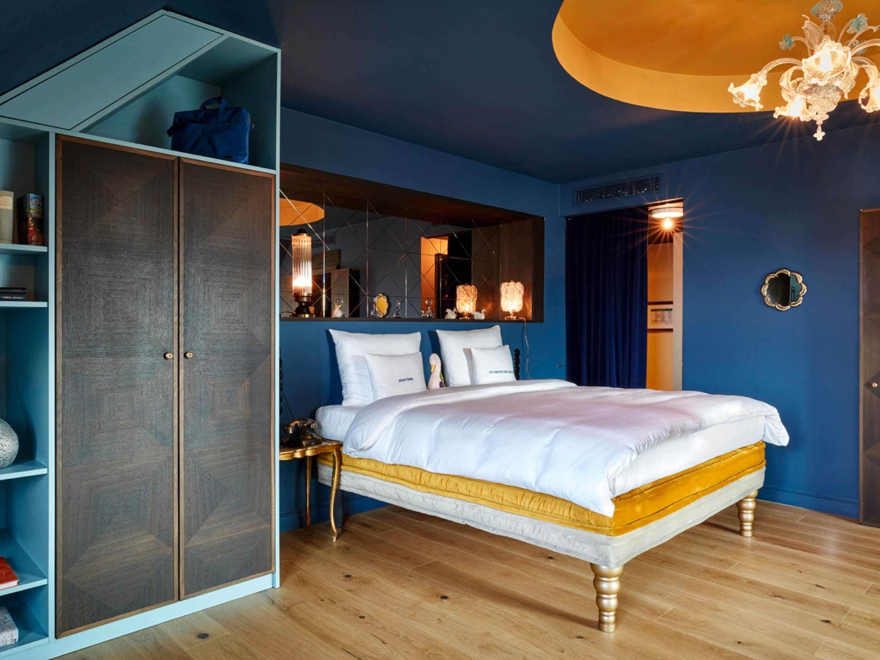 A bedroom with a bed, wardrobe, bedside table, and a mirror.