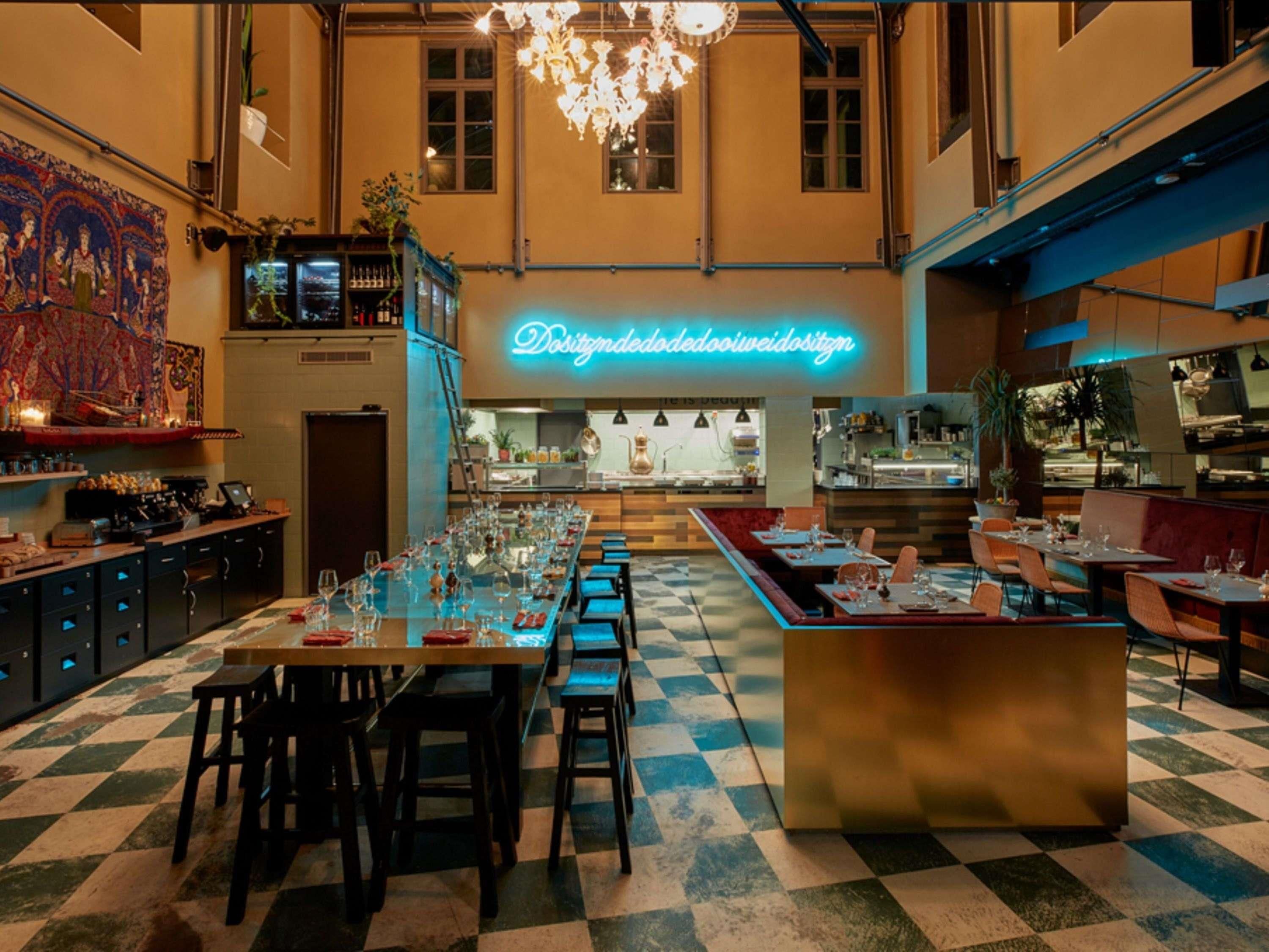 A restaurant with a checkered floor, a neon sign, and a bar area.