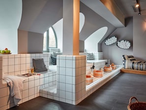 A modern bathroom with a tiled bench, wooden buckets, and a large window.