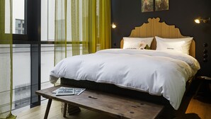 Een net opgemaakt bed met witte lakens, een houten hoofdbord en twee wandlampen.