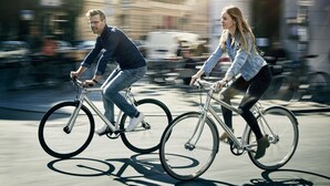 Deux personnes font du vélo dans une rue de la ville.