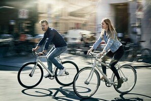 Zwei Personen fahren auf Fahrrädern auf einer Stadtstraße.
