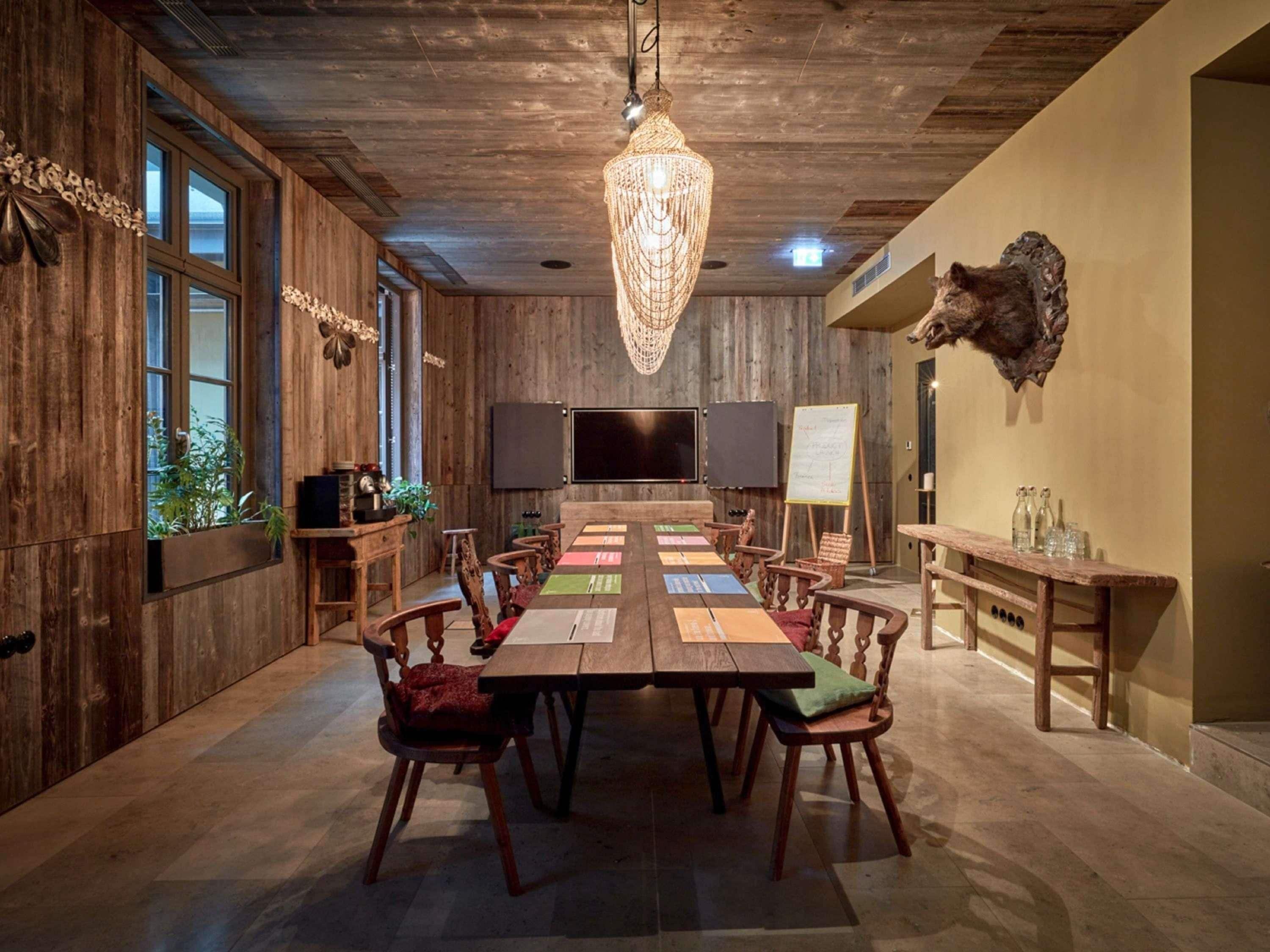 A conference room with a long table, chairs, a chandelier, a mounted animal head, and a whiteboard.