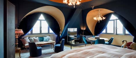 Ein modernes Schlafzimmer mit einem großen Bett, einem Schreibtisch und einer Sitzecke mit Blick auf die Stadt.