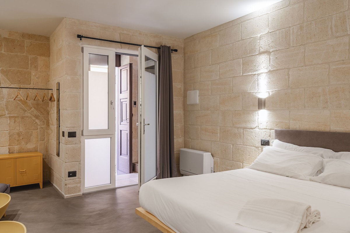 A hotel room with a bed, a wardrobe, a bathroom, and a shower area.