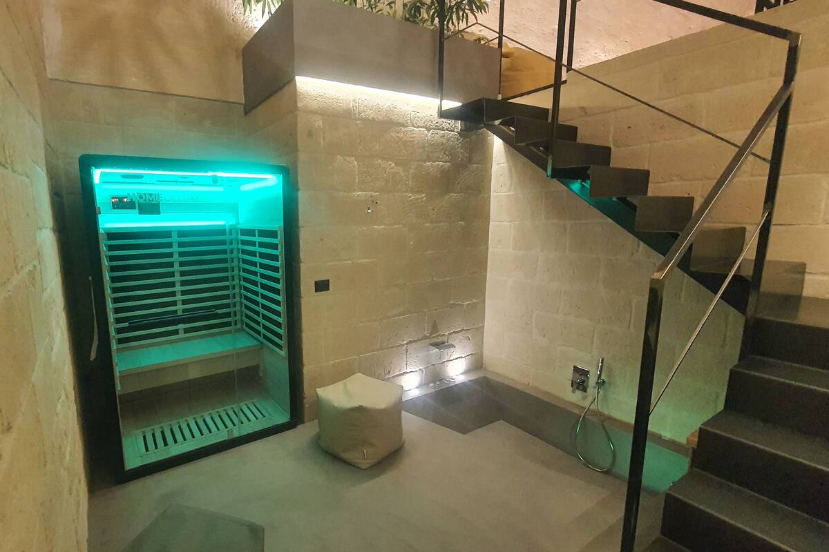 A modern staircase with a glass railing and a built-in air conditioning unit with a green light.