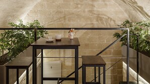 A small table with a cup and saucer, a vase with flowers, and a number '6' on a wall. - Hydria Residence (Matera)