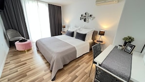 Ein modernes Hotelzimmer mit Bett, Nachttischen, einem Schreibtisch und einem Sessel.
