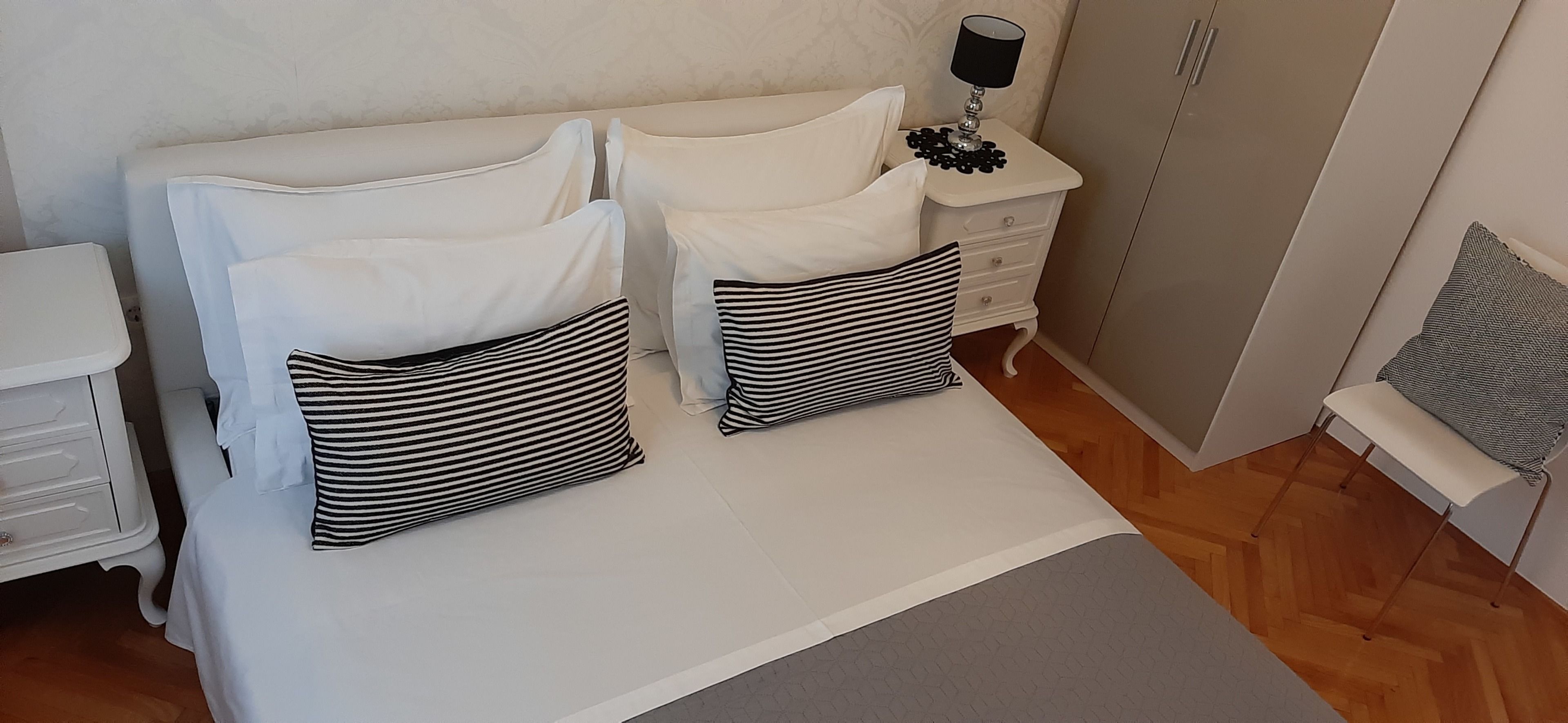 A bedroom with a bed, two bedside tables, a lamp, and a nightstand.