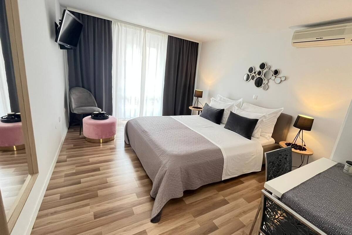 Moderni hotellihuone, jossa on suuri sänky, työpöytä, tuoli ja pieni pöytä.
