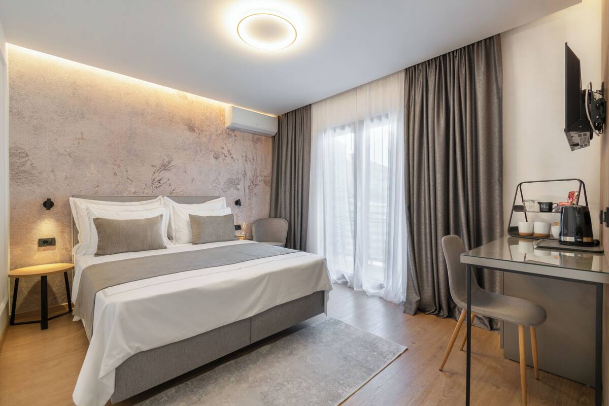 Moderni hotellihuone, jossa on suuri sänky, työpöytä tuolilla ja seinälle asennettu televisio.