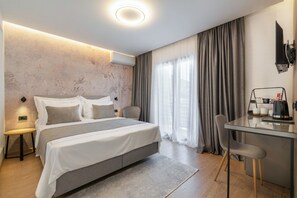 A modern hotel room with a large bed, a desk with a chair, and a television mounted on the wall. - Guesthouse Civljak (Baska Voda)
