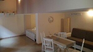 A dining area with a table and chairs, a sofa, and a wall clock. - Central Suites (Catania)