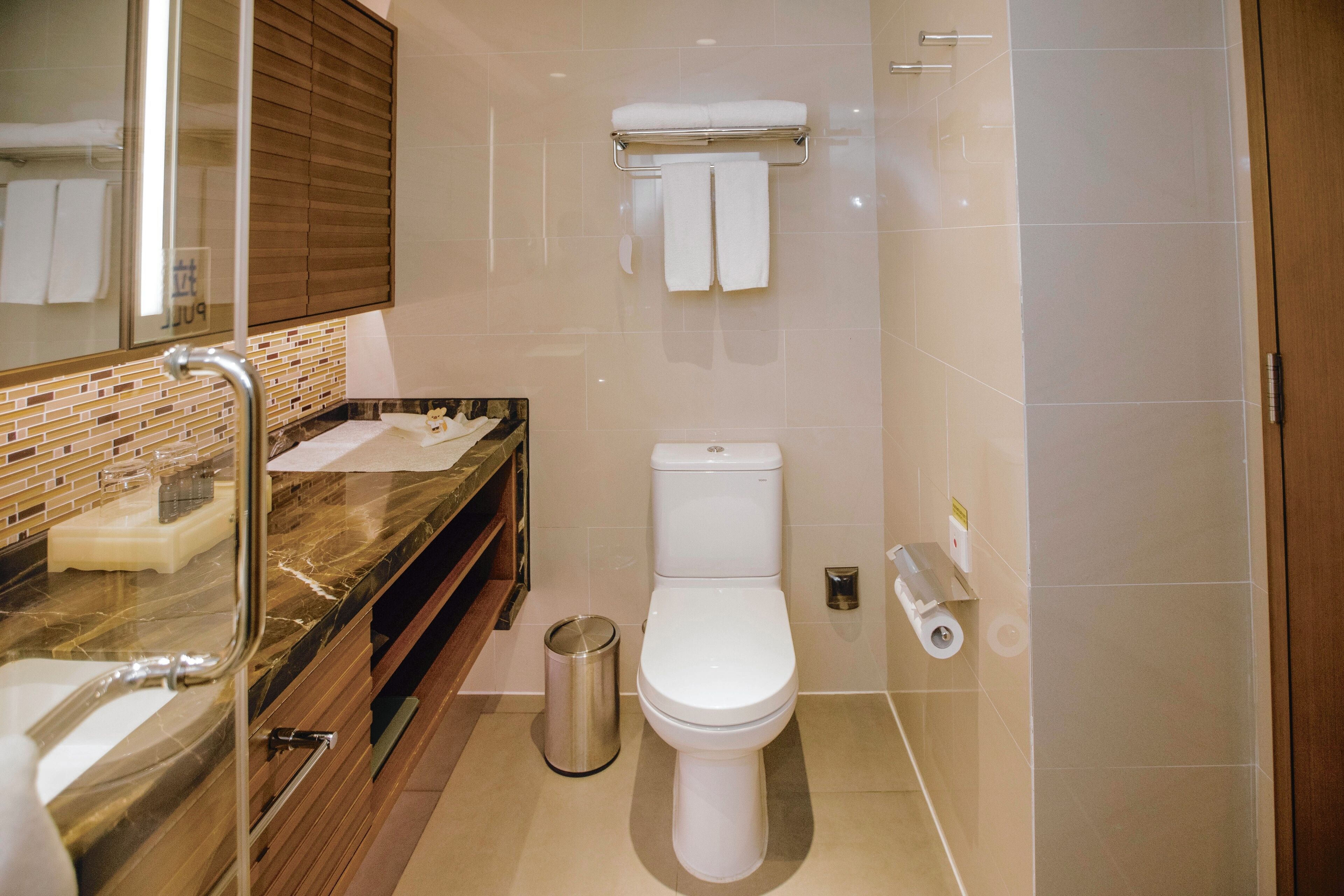 Une salle de bain moderne avec un lavabo en marbre, des toilettes et une poubelle.