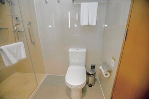 Un baño moderno con inodoro, un cubo de basura y una zona de ducha.