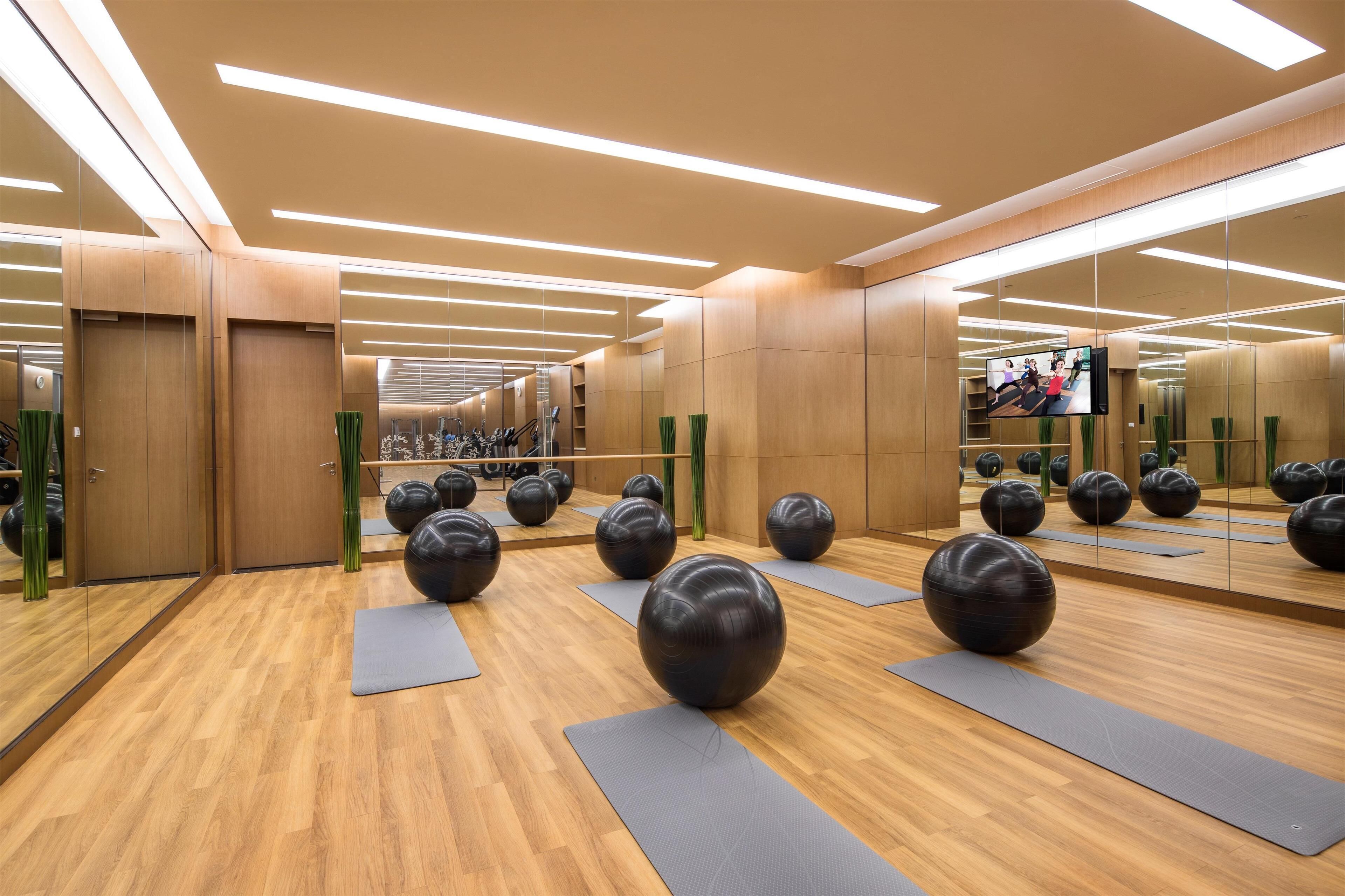 A gym with exercise balls, wooden floors, and mirrors.