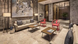 A spacious lobby with a large abstract painting, a sofa, two red chairs, and a coffee table. - Somerset Swan Lake Hefei (Hefei)