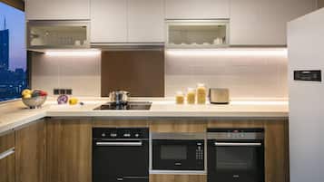 A modern kitchen with built-in appliances, including a dishwasher, oven, and microwave, with a city view through the window.