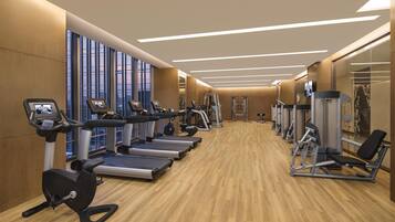 Un gimnasio con cintas de correr, elípticas y equipo de pesas.