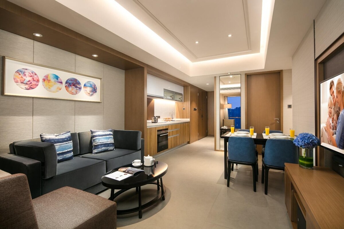 A modern living room with a sofa, coffee table, and dining area with chairs and a table.