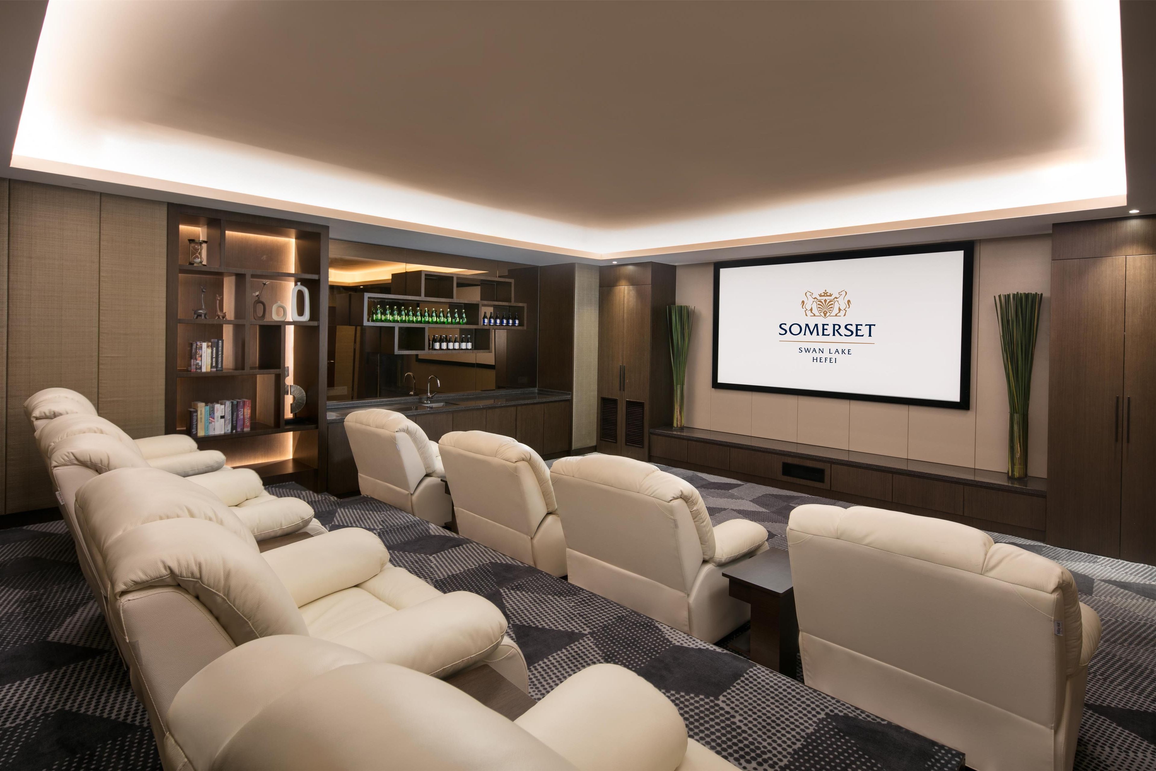 Un cinéma maison moderne, doté d’un long canapé, d’un coin bar et d’un écran affichant le logo « SOMERSET SWAN LAKE HBFI ».