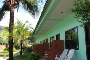 A hotel corridor with a green exterior, brick walls, and white chairs. - Baantonsai Garden Resort (Phuket)