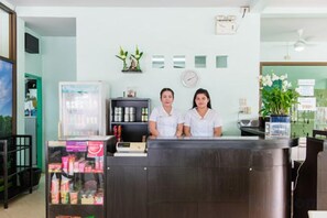 A reception area with a reception desk, a refrigerator, a shelf with products, and a clock on the wall. - Baantonsai Garden Resort (Phuket)