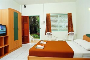 Une chambre d’hôtel avec un lit, une armoire, une télévision et une fenêtre avec des rideaux.