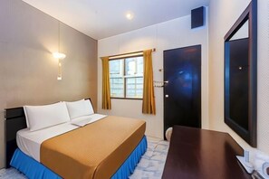Una habitación de hotel con una cama, un escritorio, una ventana con cortinas y una puerta.
