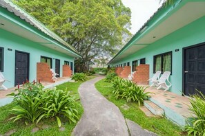 A pathway leading to a row of rooms with brick steps and green walls, surrounded by lush greenery. - Baantonsai Garden Resort (Phuket)