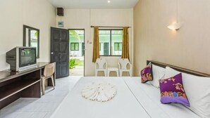 Ein Hotelzimmer mit einem Bett, einem Schreibtisch mit Fernseher, einem Sessel und einem Fenster mit Vorhängen.