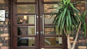 A double wooden door with glass panels and a potted plant in front. - Langholm (Cape Town)