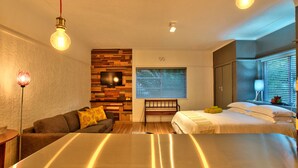 A modern hotel room with a large bed, a sofa, a TV, and a wooden accent wall. - Langholm (Cape Town)