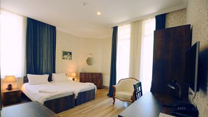 Een hotelkamer met een tweepersoonsbed, een bureau met een computer, een stoel, een kast en een televisie.