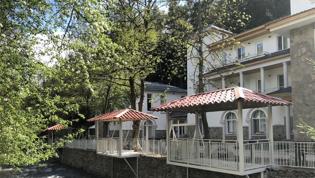 Hotel aan de rivier met buitenzitplaatsen en een stenen steunmuur.
