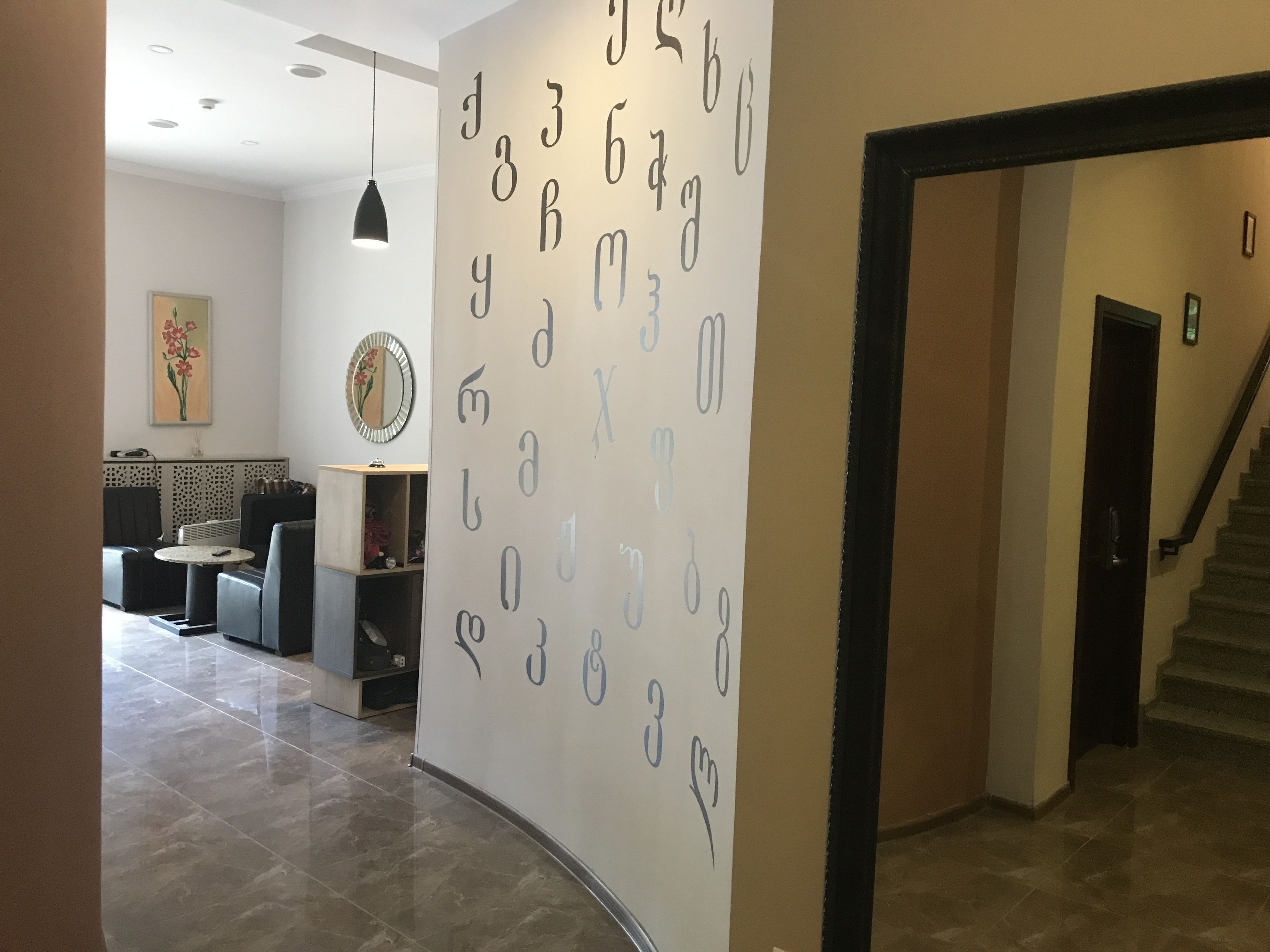 A modern lobby with a wall decorated with large numbers and letters, a round table, and a staircase.