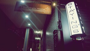 A hostel sign with the name "StaYing's Hostel" and a compass symbol. - Staying Hostel (Bang Phli)
