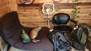 A cozy room with a wooden wall, a black chair, a brown couch, and a green bottle. - Staying Hostel (Bang Phli)