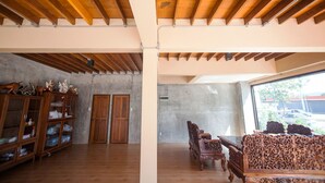 Un'ampia stanza con travi in legno a soffitto, una grande finestra con vista sull'esterno e un mobile tradizionale in legno con vetrate.