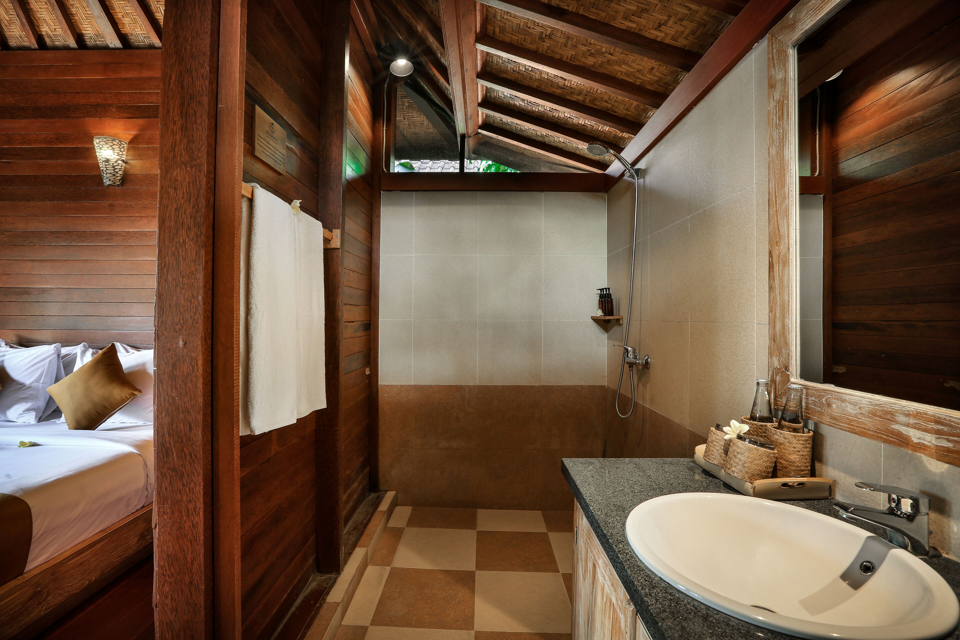 A wooden interior with a bed, a bathroom with a sink and mirror, and a checkered floor.