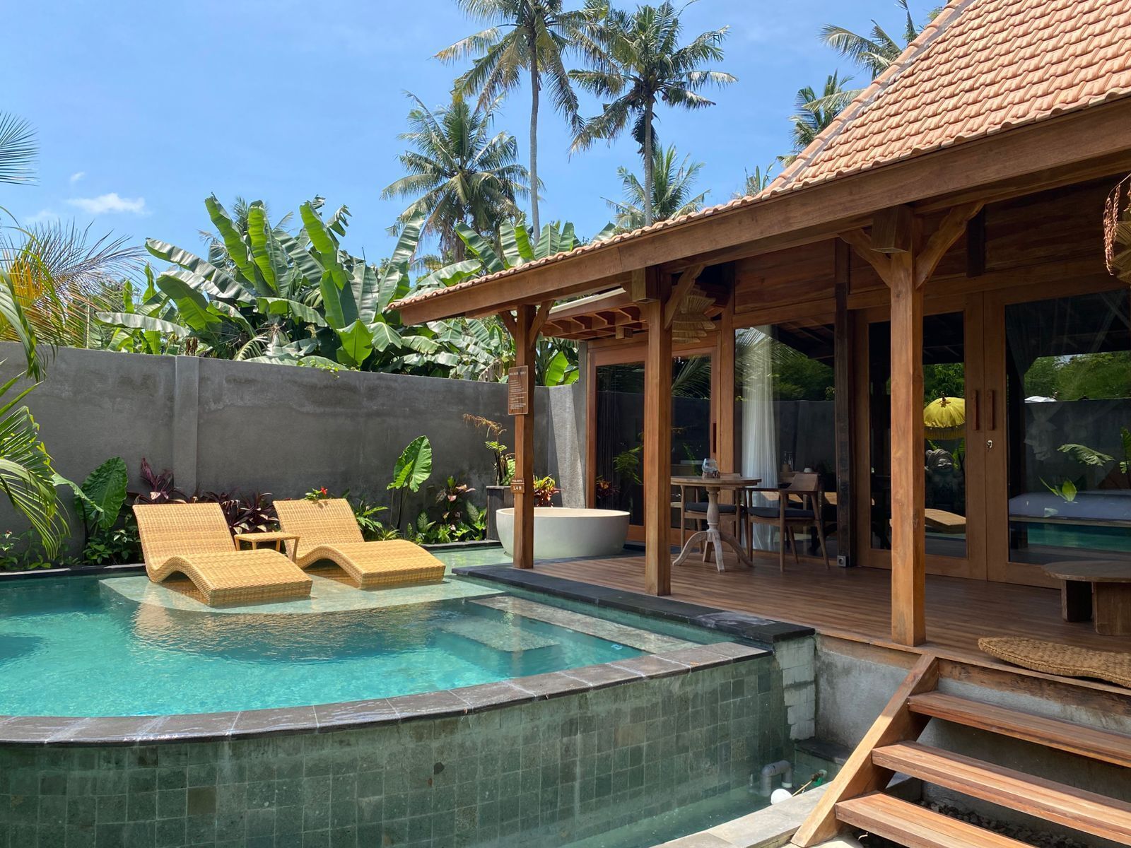 A pool area with lounge chairs, a wooden deck, and a covered seating area.