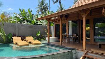A pool area with lounge chairs, a wooden deck, and a covered seating area.