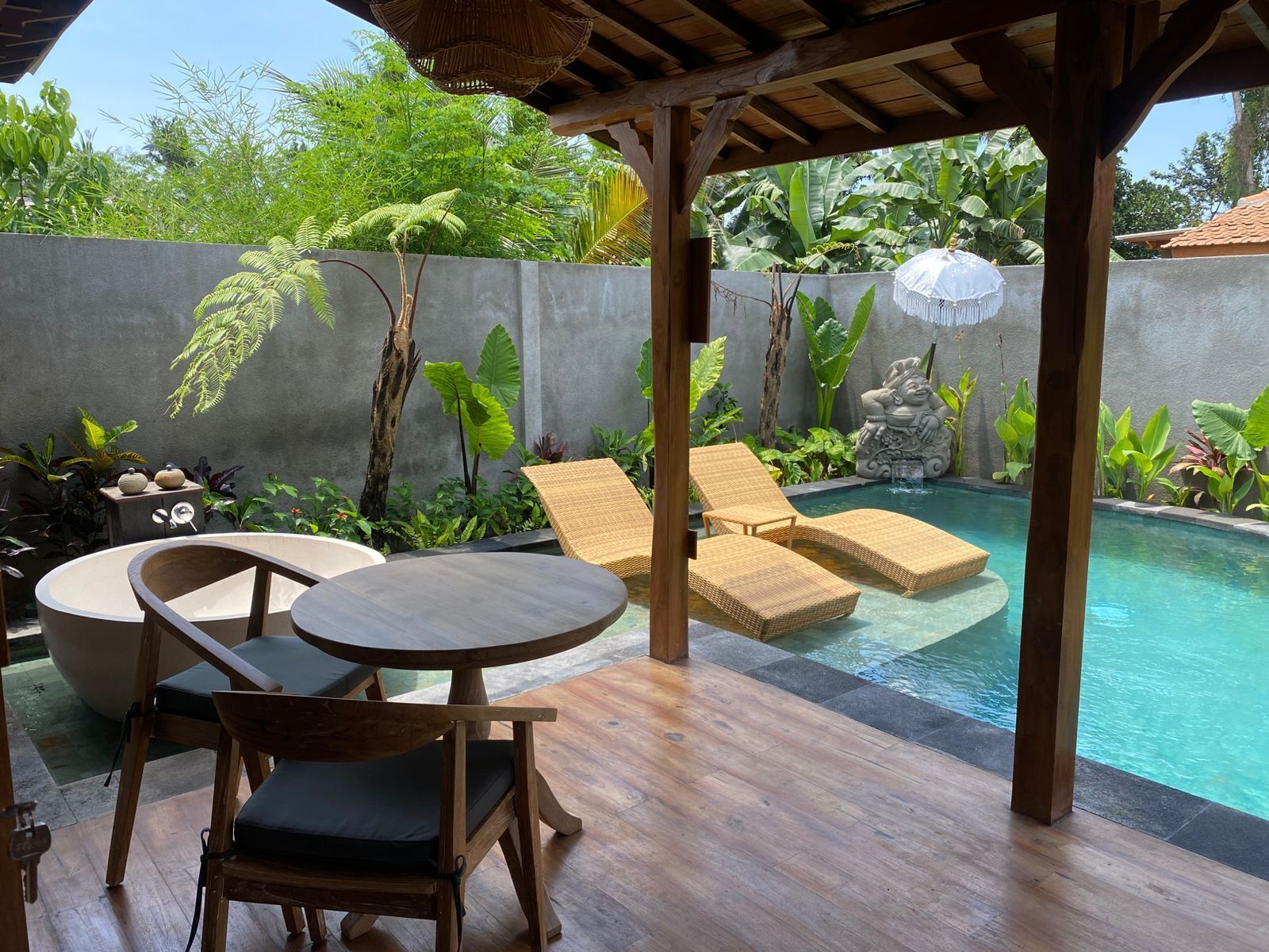 A pool area with lounge chairs, a table, and a tiki statue.